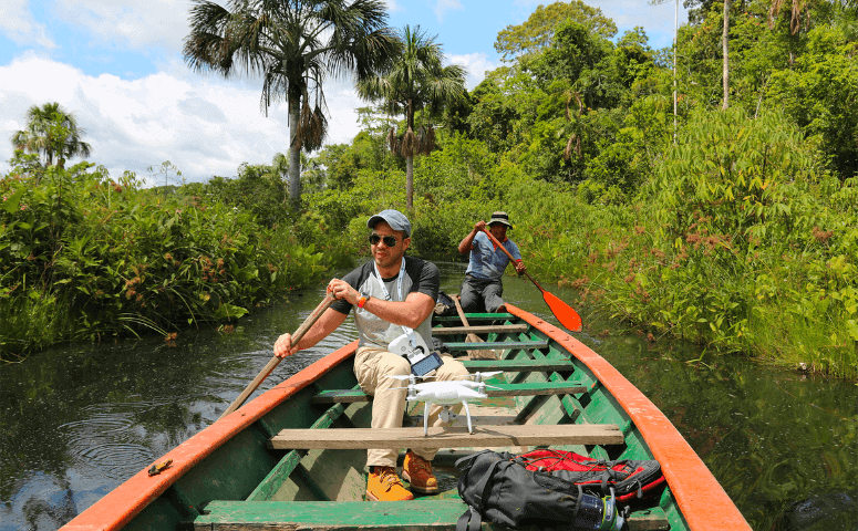 Pink Dolphins in the Amazon - Where to See Pink Dolphins in the Amazon traveler in wooden boat surrounded by jungle